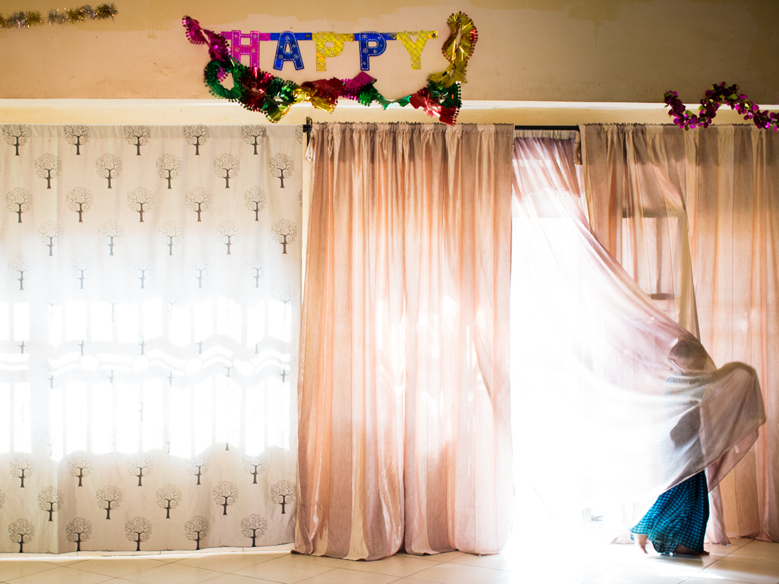 A young Somali refugee girl gets trapped in a curtain at her grandmother's house in Kisenyi, Kampala's neighbourhood with the highest number of Somali migrants. The girl is waiting to be reunited with her mother who has already been resettled to Scandinavia and is waiting for her three children to follow her.